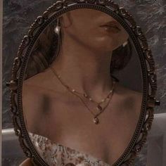 a woman's reflection in a mirror with jewelry on her neck and necklaces around her neck