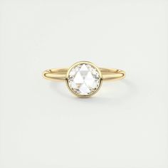 a gold ring with an oval cut diamond in the center, on a white background