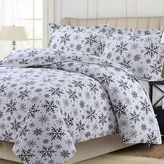 a bed with white and black snowflakes on the comforter is in a room