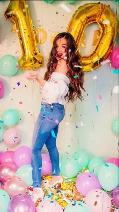 a woman standing in front of balloons and confetti with the number 10 on it