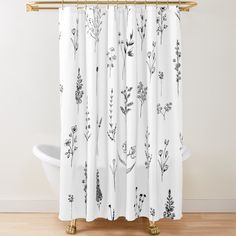 a white shower curtain with black and white flowers on it, in front of a bathtub