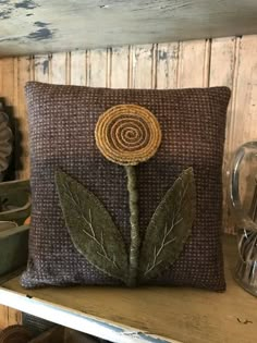 a pillow with a flower on it sitting on top of a shelf next to other items