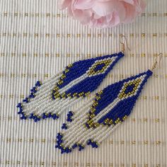 two blue and white seed beaded earrings next to a pink peonie flower