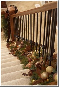 christmas garland on the bannister railing with lights and ornaments hanging from it's handrail