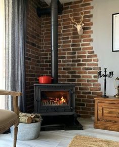 a wood burning stove in a living room next to a chair and table with a deer head on the wall