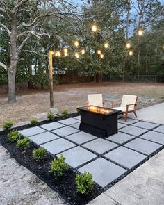 an outdoor fire pit surrounded by chairs and lights