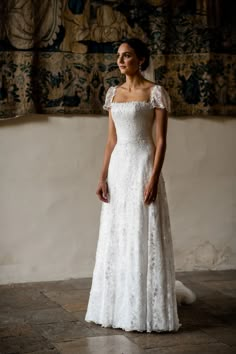 a woman in a white wedding dress standing next to a wall with paintings on it