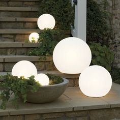 three white lights sitting on top of steps next to a bowl filled with green plants