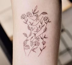 a woman's arm with flowers and leaves on the left side of her body