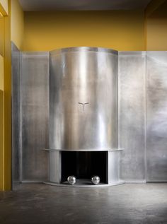 a large metal object in a room with yellow walls and concrete flooring on the ground