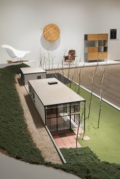 a model of a house on display in a room with green grass and fake trees