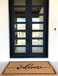 a welcome mat with the word welcome on it in front of a door and windows