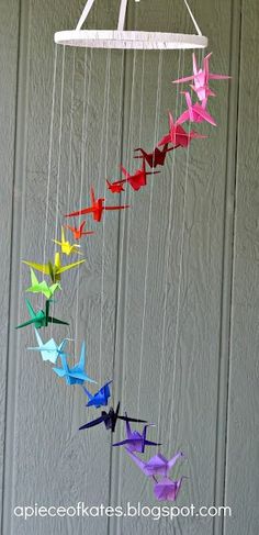 an origami bird mobile hanging from a string in front of a door with the words, paper cranes on it