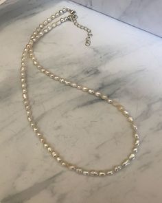 This beautiful and dainty necklace is strung with genuine freshwater rice pearls and finished with a sterling silver clasp. It is 16 1/2" with a 2" extender chain. Silver Pearl Beaded Necklaces With Tiny Beads, Silver Pearl Beaded Necklace With Tiny Beads, Classic Single Strand Beaded Necklace, Classic Adjustable Single Strand Beaded Necklace, Dainty Everyday Beaded Pearl Necklace, Everyday Silver Single Strand Pearl Necklace, Dainty Silver Beaded Necklace With Pearl Chain, Classic Adjustable Beaded Pearl Necklace, Beaded Pearl Necklace With Oval Beads