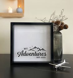 an airplane is sitting on the table next to a framed sign that says my adventures