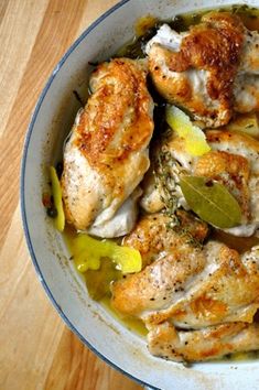 a bowl filled with chicken and vegetables on top of a wooden table