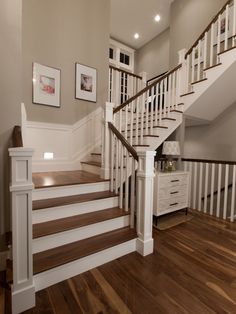 a staircase with white railings and wood flooring in a large home's entryway