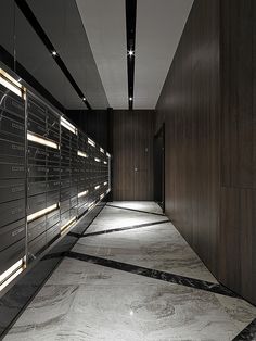 an empty hallway with lots of lockers and lights on the wall behind each door