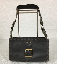 "Here we have a vintage brown leather footed Purse with a wide strap, metal studs and large buckle. This has a great retro look. This is in very nice condition considering its age. I noticed some light scratches but no ther problems. It measures: Height - 6\" Width - 9 3/4\" Depth - 4 1/4\" Strap Drop - 11 1/4\" I try my best to give accurate descriptions, although I am no expert, plus I'm human and sometimes I might miss a flaw. I always provide high resolution photos and consider them to be pa Brown Leather Shoulder Bag With Buckle Closure, Leather Satchel Shoulder Bag With Rivets, Vintage Leather Bags With Metal Hardware, Vintage Black Shoulder Bag With Metal Hardware, Retro Leather Shoulder Bag With Metal Hardware, Brown Leather Bags With Rivets, Vintage Leather Bags With Hardware Details, Brown Leather Bags With Hardware, Leather Shoulder Bag With Rivets For Daily Use