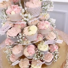 a tiered cupcake display is decorated with pink and white frosting, baby's breath