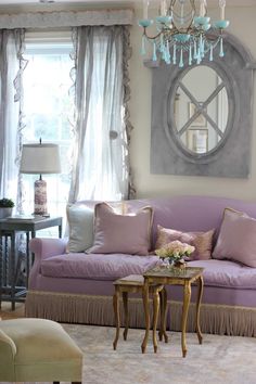 a living room filled with furniture and a chandelier hanging from the ceiling next to a window