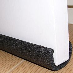 a cat laying on the floor next to a white wall and black mat under it