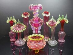 an assortment of glass vases and candlesticks on a black table with reflections