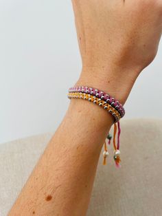 a woman's arm wearing a bracelet with beads and tassels on it