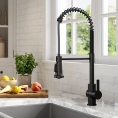 a kitchen sink with a black faucet and fruit on the counter next to it