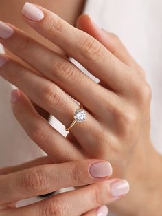 a woman's hand holding a ring with a diamond on it and her left hand