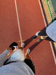 two people standing on a tennis court with their feet in the air and one person wearing sneakers