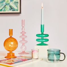 a table topped with candles and other items on top of a white counter next to a painting