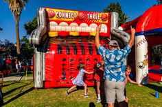 two people standing in front of a giant candy machine at an amusement park, with one person reaching up to grab something out of the top