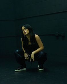 a woman kneeling down in the dark with her hands on her knees