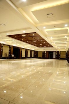 an empty room with white marble flooring and lights on the ceiling is lit by recessed lighting