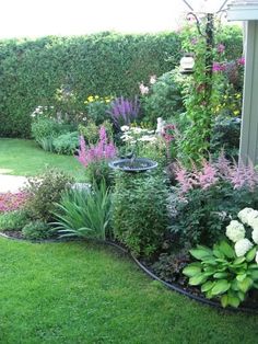 a garden filled with lots of different types of flowers and plants next to a house