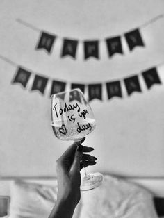 a person holding up a wine glass in front of a bunting banner with words on it