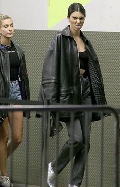 two women are walking down the street in black leather jackets and high waisted jeans