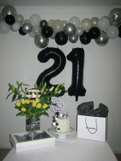 a table topped with balloons and flowers next to a number one cake on top of a plate