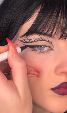 Uma mulher branca fazendo um delineado que imita uma teia de aranha com batom vermelho e preto Halloween Eyeliner Ideas, Halloween Eyeliner, Goth Eye Makeup, Funky Makeup, Indie Makeup, Halloween Eye Makeup, Halloween Makeup Inspiration, Swag Makeup, Doll Makeup