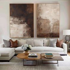 a living room filled with furniture and two paintings on the wall above it's coffee table