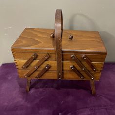 an old wooden chest with metal handles and knobs on it's sides sitting on a purple surface