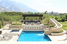 an outdoor swimming pool surrounded by stone walls and steps leading to a covered patio area