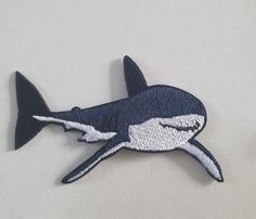 a patch with a shark on it sitting next to another patch in the shape of a fish