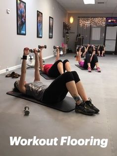 a group of people doing exercises on exercise mats in a gym with dumbbells