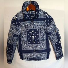 Introducing The Limited Edition Rich Boys Paisley Blue Bandanna Puffer Jacket Windbreaker, Perfect For Your Little Boy Who Wants To Stay Warm And Stylish. Made Of 100% Polyester, This Puff Coat Features A Paisley Pattern And Has Button Pockets On Sleeves. This Outerwear Is Designed For Boys In Size 8 And Is Suitable For Various Occasions. Very Versatile Stylish Jacket. Don't Miss Out On This One As It's A Sold Out Item! See Pictures For Additional Details And Feel Free To Ask Questions! Navy Cotton Outerwear For Winter, Fitted Hooded Patchwork Outerwear, Fitted Cotton Outerwear For Cold Weather, Quilted Blue Hooded Outerwear, Blue Quilted Hooded Outerwear, Navy Patchwork Outerwear For Streetwear, Blue Cotton Outerwear For Winter, Blue Winter Outerwear, Fitted Blue Outerwear For Outdoor