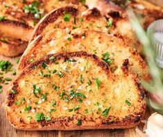 four slices of garlic bread on a cutting board with parsley sprinkled on top