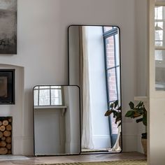 three mirrors sitting on top of a wooden floor next to a fireplace in a living room