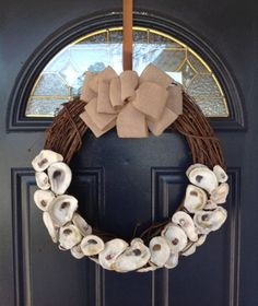 a wreath made out of seashells hangs on the front door's black door