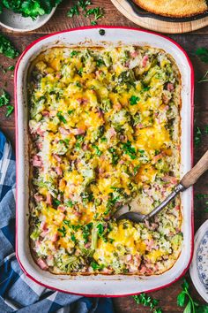 a casserole dish with ham, cheese and broccoli in it on a wooden table